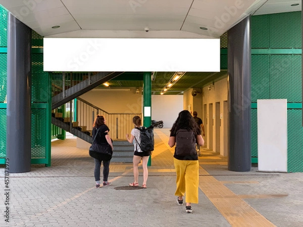 Obraz People walking toward train station with white billboard