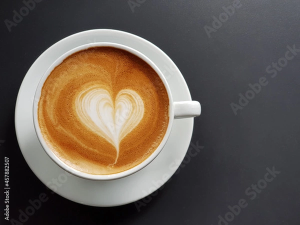 Obraz Perfect cup of cappuccino with latte art heart in white cup on black table background.