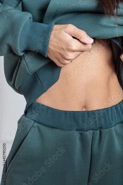 Fototapeta Woman in green tracksuit. Warm clothing for autumn or winter. Soft, comfortable elastic band on the pants