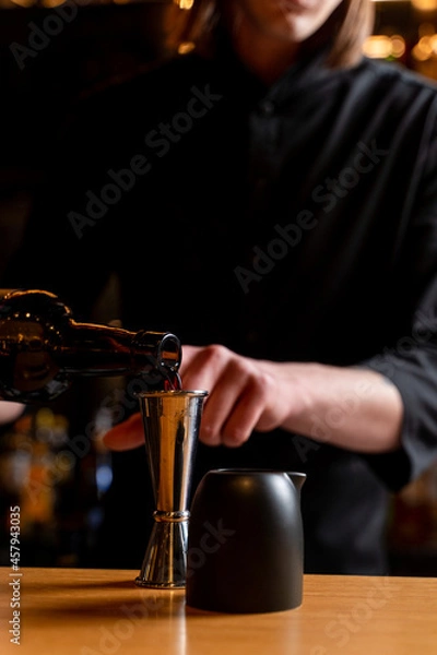 Fototapeta Bartender is making a cocktail, hands only visible, wooden bar counter