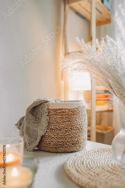 Fototapeta Light interior made of natural eco components. Wicker straw basket for storing clothes, Boho style room