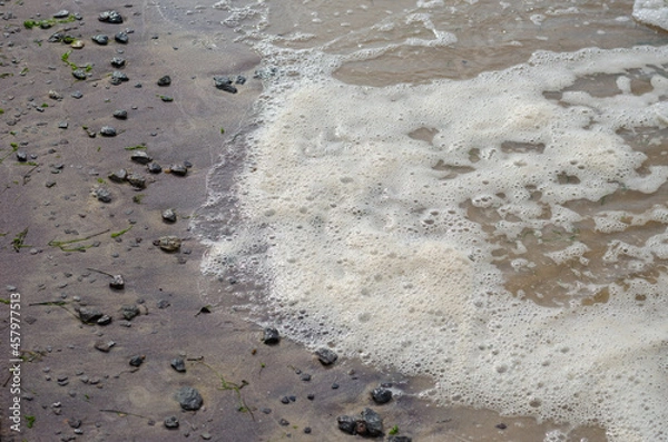 Obraz Sandy beach after the storm at sunset. Muddy Shoreline with pebbles and algae. August, evening time. Angled view from above. Selective focus. Blurred motion.