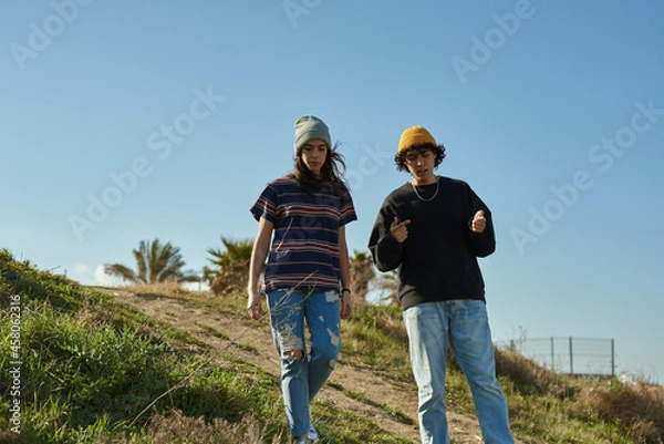 Obraz Two captivated young people walking down a hill