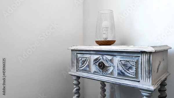 Obraz Bedside table with lamp in a white room. Minimalist and rustic decor.