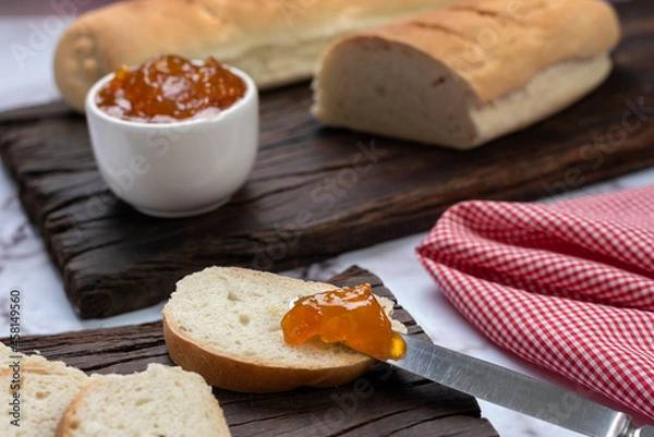 Fototapeta snack or breakfast with homemade sweet fruit jam in white bowl with slices of homemade bread on wooden board