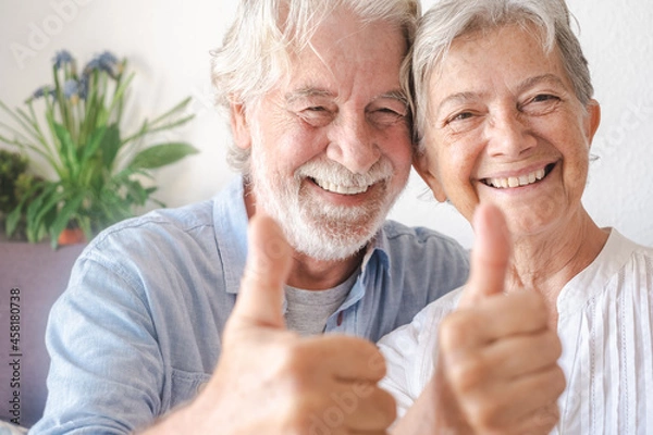 Obraz Beautiful senior couple  looking at camera gesturing positive sign. Serene elderly people enjoying retirement