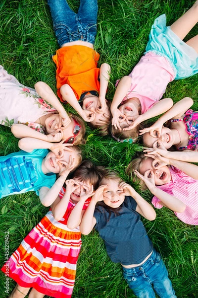 Obraz A group of children lying on the green grass in the Park. The interaction of the children.