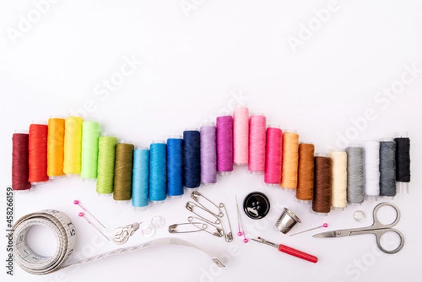 Fototapeta Colorful threads and sewing accessories on a white background. Sewing background
