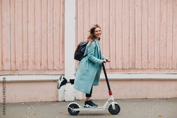 Fototapeta Young woman with electric scooter at the city.
