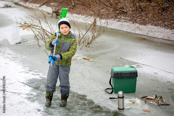Obraz little fisherman stands on ice in winter