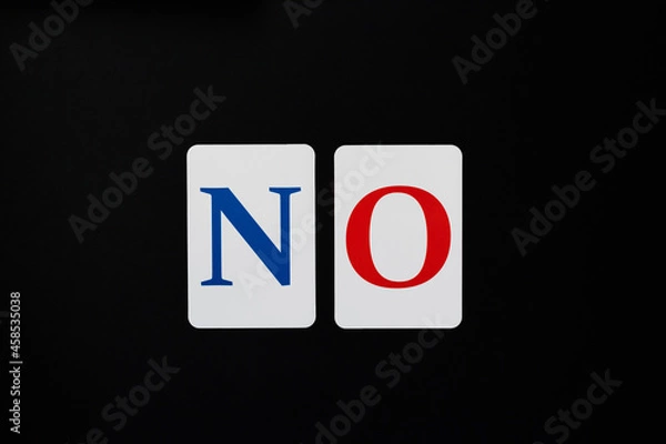 Fototapeta The word no made up of blue and red letters on white cards laid out in a line on a black background