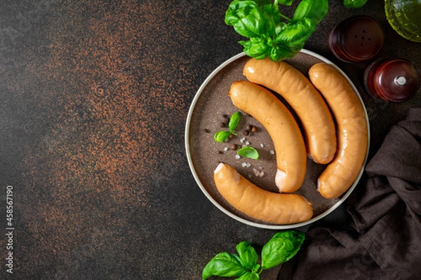 Obraz Pork sausages in a plate on a dark culinary background top view	