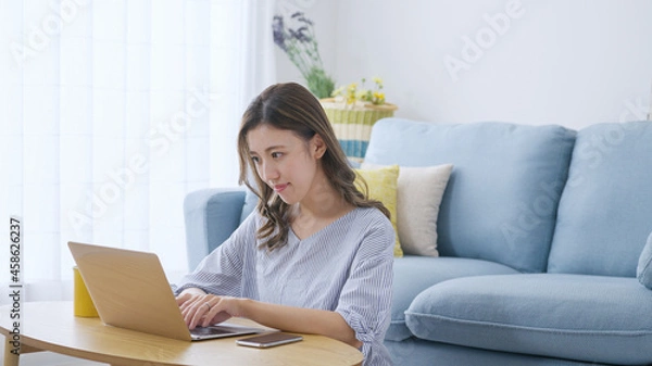 Fototapeta 家でパソコンを操作する若い女性