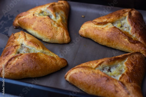 Obraz 
Photo of four ruddy triangular pies on a baking sheet, just taken out of the oven