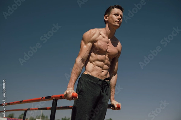 Obraz  athlete man doing triceps dips on parallel bars in outdoor exercises. Calisthenic. Street workout
