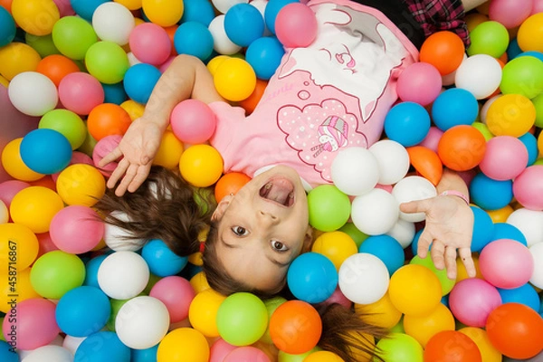 Obraz a girl is lying on a children's playground in colorful balloons