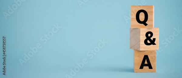 Fototapeta Close up shot of Q and a wooden blocks on panorama blue background with copy space.