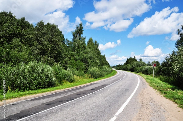 Fototapeta Panoramic view of a deserted road. Hit the road. Beautiful clouds in the sky.