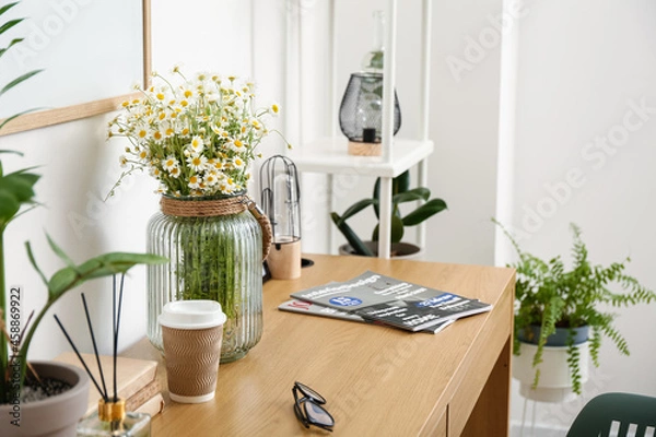 Fototapeta Modern workplace and vase with chamomiles near light wall