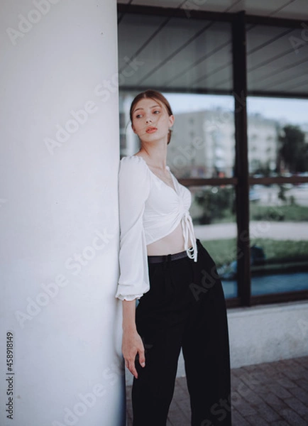 Obraz a beautiful girl in a white shirt walks around the city, a model girl in the city