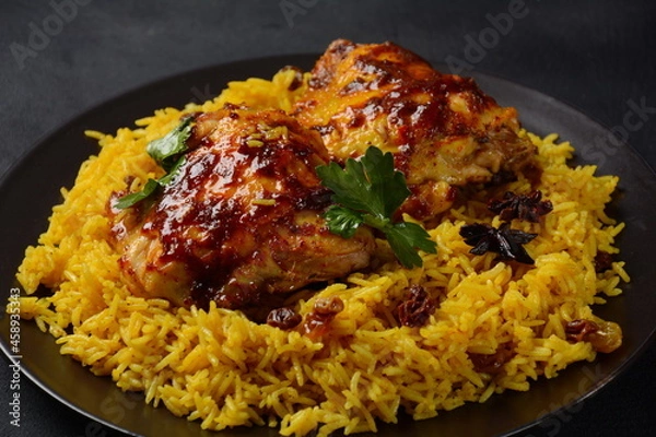 Fototapeta The national Saudi Arabian dish chicken kabsa with roasted chicken quarter and almonds, raisins, garlic and biryani rice