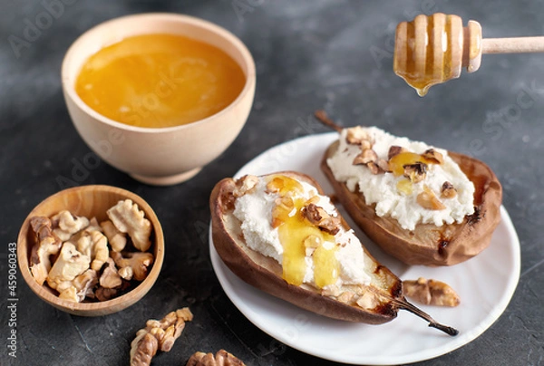 Fototapeta autumn menu dessert, baked pears with ricotta and nuts and honey topping. walnuts and honey in wooden plates on grey table. sweet comforting food for fall season.