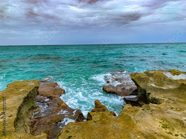 Fototapeta waves crash onto rocky shore on the beach