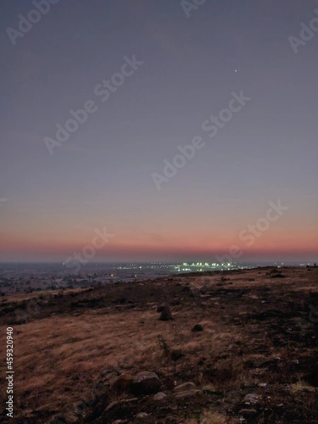 Fototapeta A scenic hill top view of Gulbarga city after sunset in arid region of deccan india with illuminated street lights from far away being seen