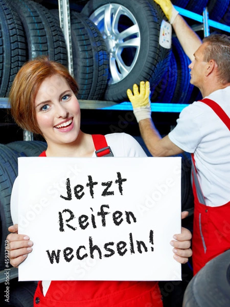 Fototapeta Female car mechanic is showing blackboard with tire changing