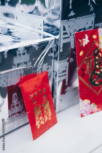 Fototapeta Poortrait orientation of red envelopes or red packets called Ang Pao or Ang Pow, also Hongbao or Hungbao in Mandarin and Lai See in Cantonese on white table. Selective focus. 