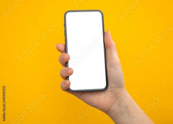 Obraz Hand with mobile phone mockup screen on a yellow background, copy space photo