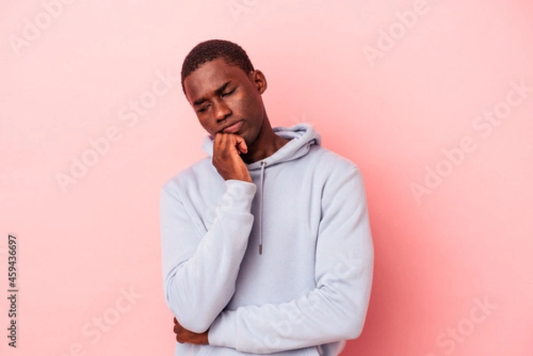 Fototapeta Young African American man isolated on pink background looking sideways with doubtful and skeptical expression.
