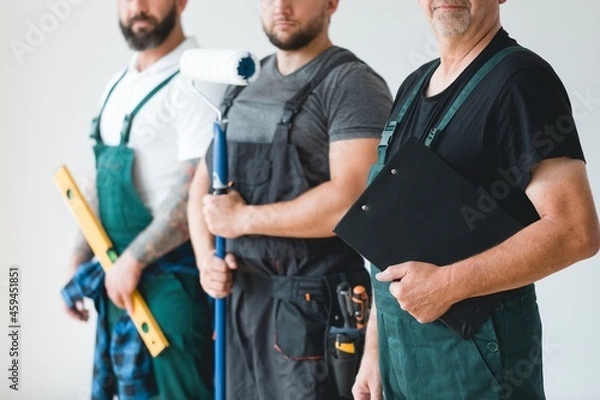 Obraz Crew of three professional builder wearing overalls standing in empty interior