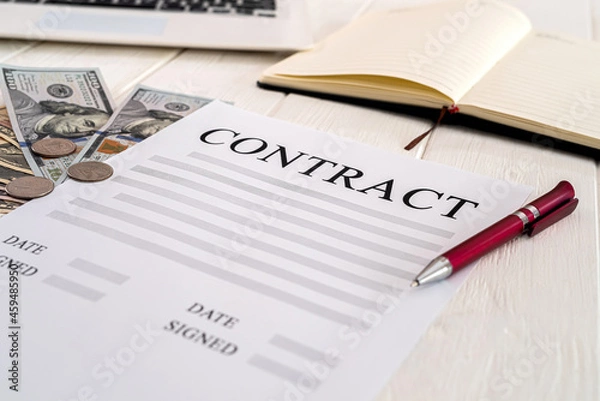 Fototapeta contract with pen and dollar bills lie on a wooden table