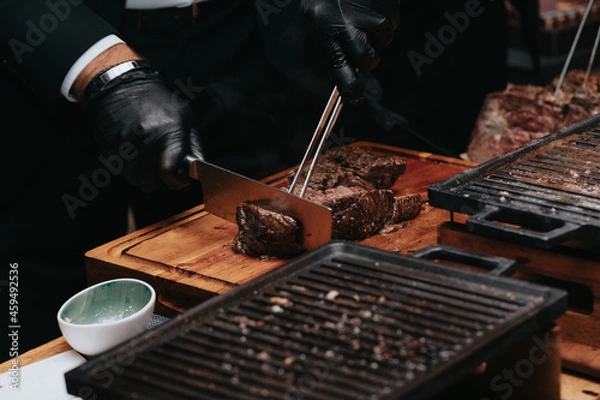 Fototapeta Cooking juicy beef steak by chef hands with copy space for text menu elegant or recipe on dark background.