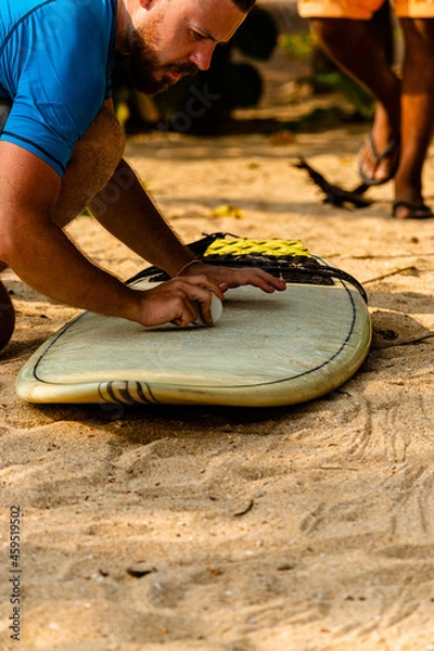 Fototapeta Surfer z deską na wybrzeżu przygotowujący się do pływania.