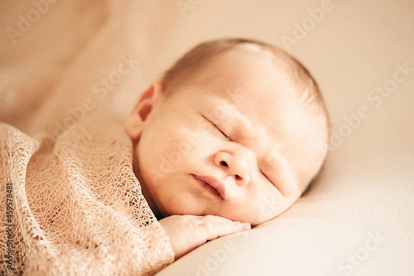 Fototapeta A newborn baby sleeping on a soft white background. Childhood or parenting concept. Soft focus, copy space.