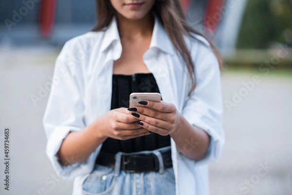 Fototapeta Close up of female hands using a smartphone.