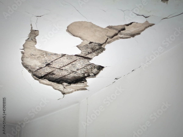 Fototapeta Cracks in the ceiling from the water pipes seeping inside the room of building. Selective focus.