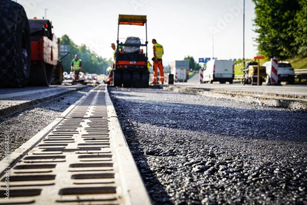 Fototapeta Sewer grate constructing drain and asphalt road in the middle of highway