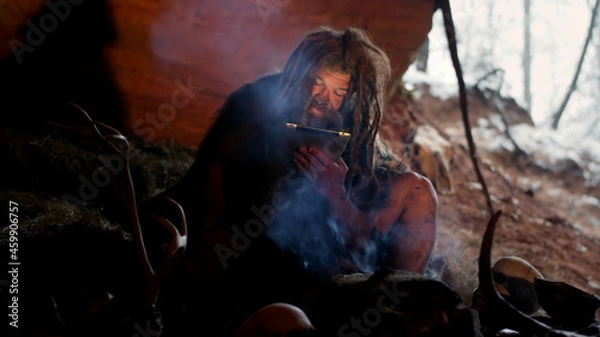 Fototapeta Caveman using tablet computer learning new things in ancient dwelling