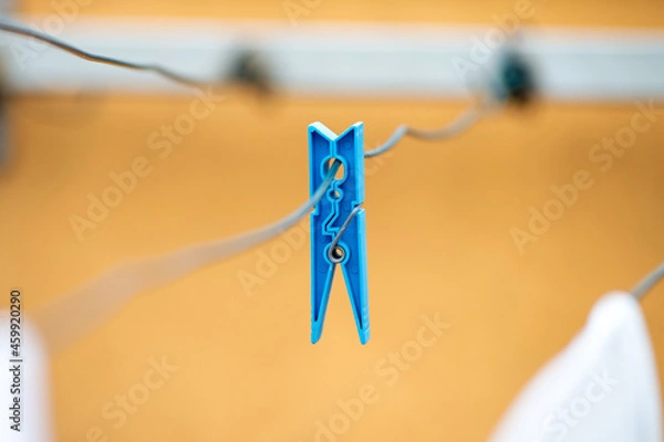 Fototapeta Close up of blue clothespin hanging on a thread 