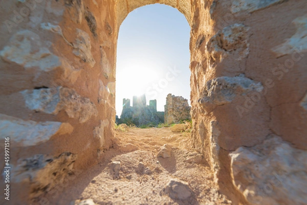 Fototapeta Castle ruins on mountain top at Rocca Calascio, view through stone window, landmark in the Gran Sasso National Park, Abruzzo, Italy. Clear blue sky sun burst in backlight