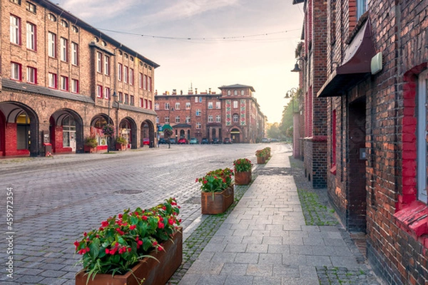 Fototapeta Traditional, silesian district Nikiszowiec. Renovated, old, brick block houses, build for coal miners in 1908-1919, cobblestone street. Beautiful, morning light. Katowice, Silesia, Poland.