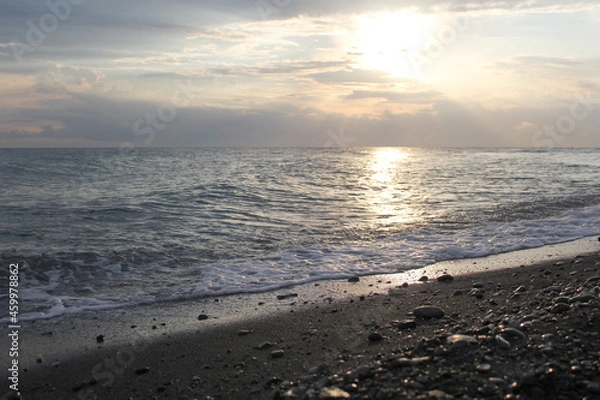 Fototapeta Sunset on the seashore. An empty beach. Calm sea at sunset. The concept of privacy and relaxation.