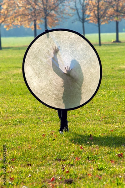 Fototapeta Full frame of little girl playing hiding in the park. Backlit silhouette 