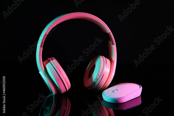 Fototapeta Modern computer mouse and headphones on dark background