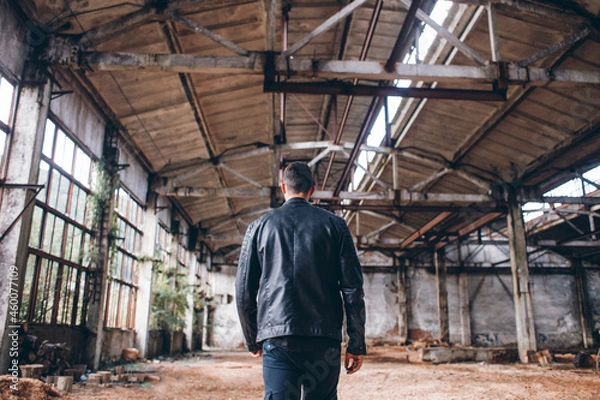 Fototapeta Handsome Man in Black Jacket in Dark Empty Abandoned Factory Hall 