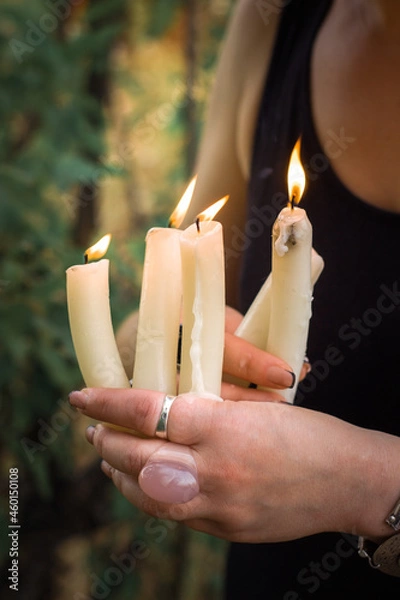 Fototapeta witchcraft rite with white candles in the hands of a witch woman