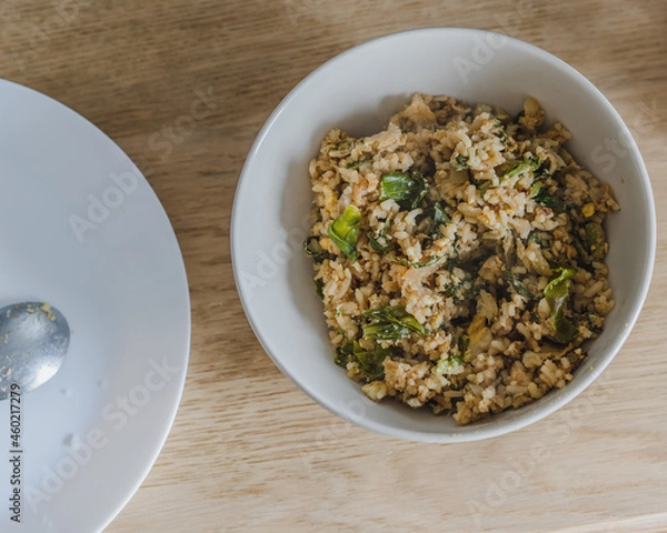 Obraz Stir fried rice with chicken ,kale ,onion, egg in a white plate on the wood table for cooking.